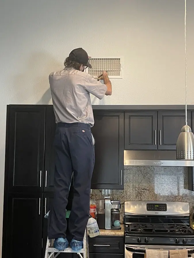 Technician inspecting an air vent during HVAC service in Killingly
